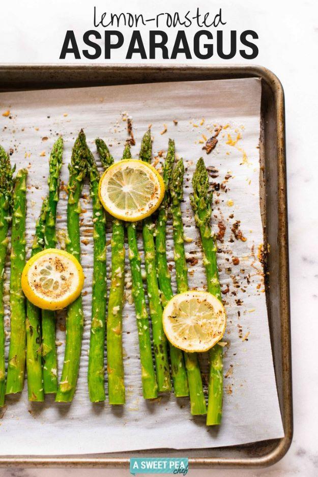 Lemon roasted asparagus on a parchment lined sheet pan with green spears and three roasted lemon rounds