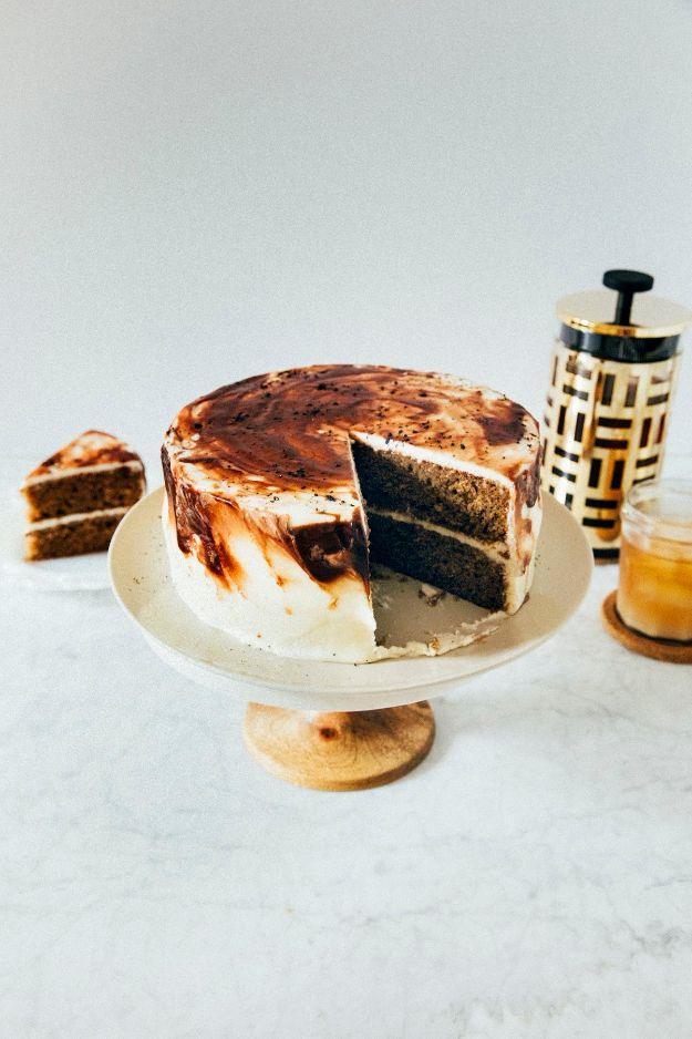 Vietnamese iced coffee cake dusted with cocoa with a wedge cut to show the dark layers, on a white cake stand