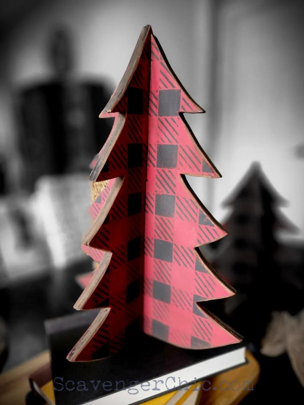 Red and black buffalo plaid wooden Christmas tree made of two slotted plywood pieces standing on a stack of books