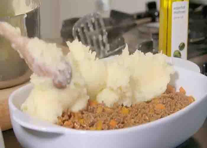 Adding the mashed potatoes over the ground beef to make the cottage pie
