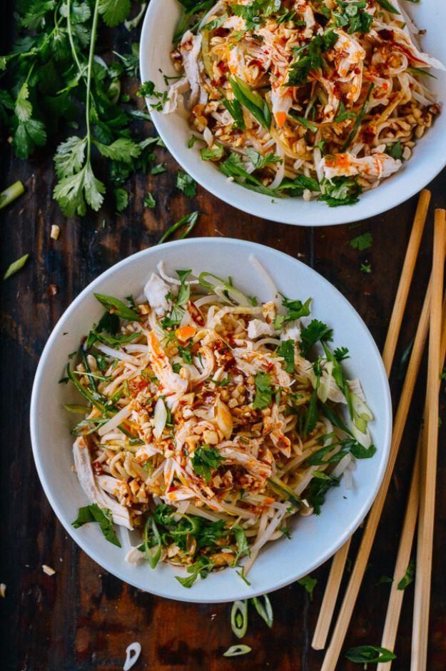 Cold noodles with shredded chicken, bean sprouts, peanuts and cilantro in two white bowls with chopsticks