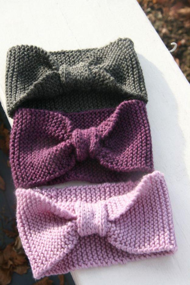 Three knitted baby headbands in olive, plum and pale pink, each gathered into a knot at the front, on stone