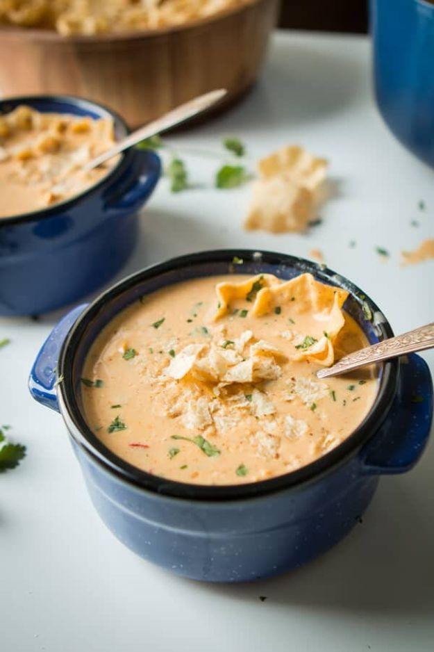 Cheesy southwestern chicken tortilla soup in a blue crock dish topped with tortilla chips and cilantro