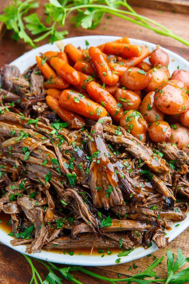 Slow cooker balsamic glazed roast beef shredded on a white platter with glazed carrots, baby potatoes and parsley
