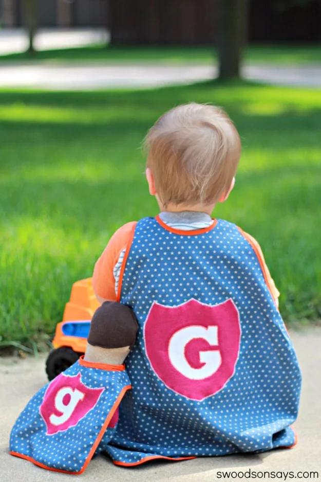 Sewing projects for boys superhero cape in blue polka dot fabric with a pink shield applique worn by a toddler on a lawn