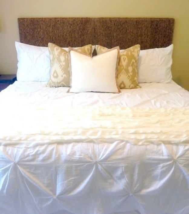 Rope headboard, a wide headboard wrapped end to end in rope above white pintuck bedding and tan ikat pillows