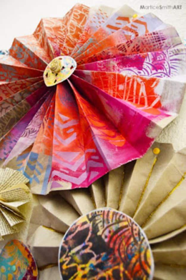 Stenciled paper fans in orange and pink layered on a wall with a round painted medallion at the center