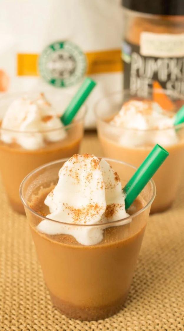 Pumpkin spice latte jello shots in clear cups topped with whipped cream and a dusting of pumpkin pie spice