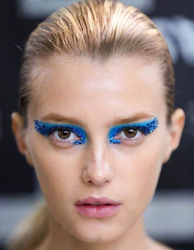 Jeweled eye Halloween makeup with bright blue shadow, rows of blue gems and dramatic black winged eyeliner