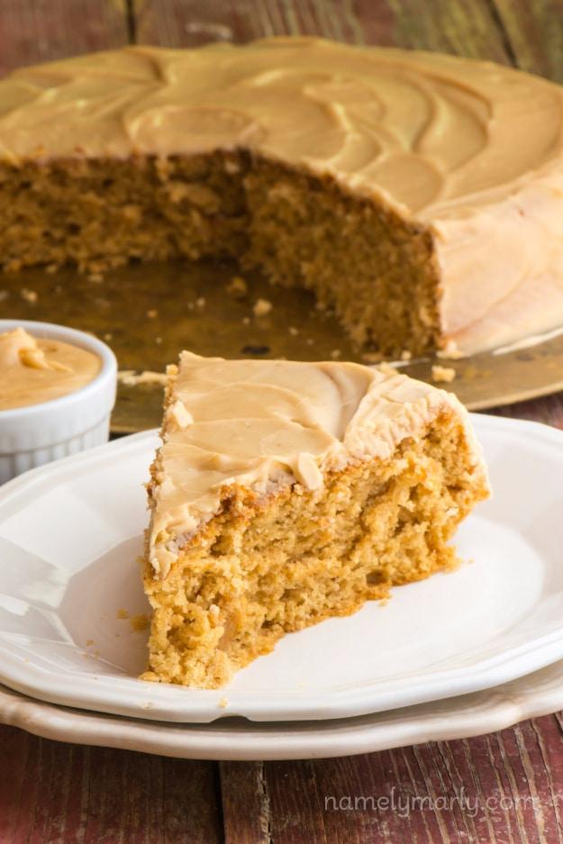 Round peanut butter wacky cake with swirled peanut butter frosting and one slice cut out onto a white plate