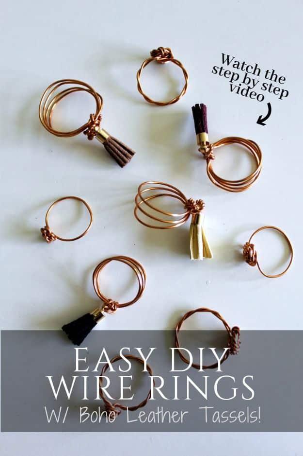 Copper wire stacking rings scattered on a pale surface, three hung with small leather tassels, typeset title below