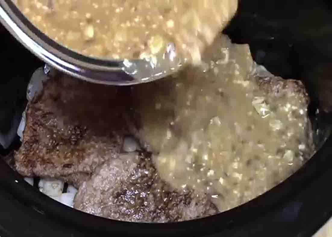 Adding the gravy sauce to crockpot with the cube steaks