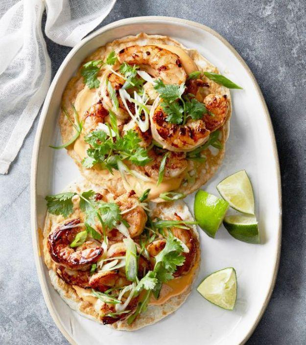 Open coconut wraps topped with grilled shrimp, scallions and cilantro on an oval platter with lime wedges