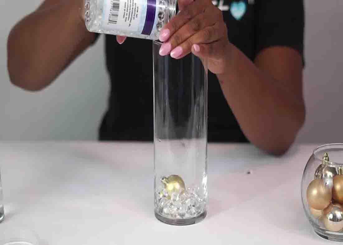 Pouring some water beads to the vase for the DIY winter wonderland centerpiece