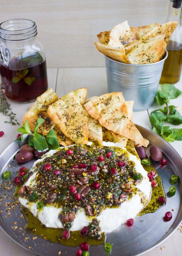 Labneh dip spread in a shallow bowl topped with zaatar, chopped pistachios, fresh mint and sliced olives