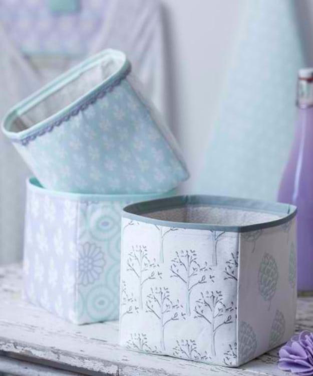 A soft canvas storage cube in natural and navy, holding folded blankets inside a white shelf unit in a bright hallway