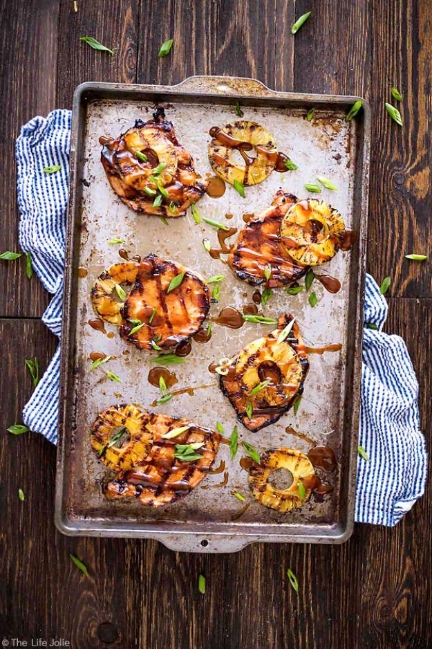 Grilled Hawaiian pork chops and charred pineapple rings on a sheet pan with scallions on dark wood boards