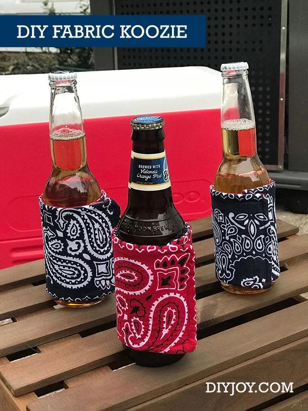 Cotton fabric koozies in mixed prints wrapped around cans with velcro tabs, lined up along a picnic table.