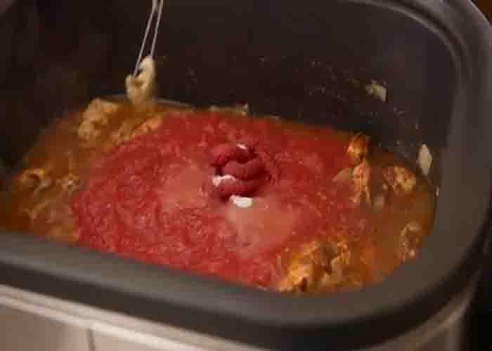 Adding the tomato sauce into the crockpot butter chicken recipe