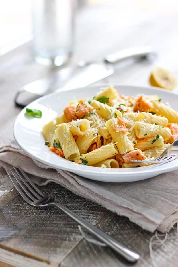 Light lemon garlic pasta with salmon, rigatoni tossed with flaked salmon, basil and shaved parmesan in a white bowl