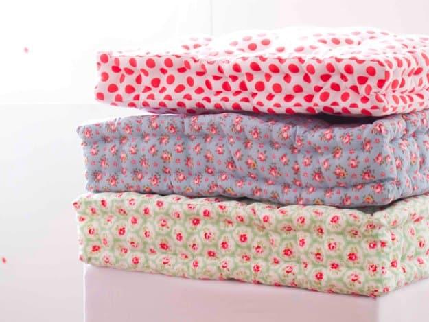 Quilted floor cushion tutorial, a stack of three tufted floral gusseted floor cushions in pink blue and green