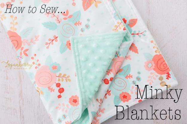 A minky baby blanket in soft gray, backed in white cotton and folded into a square on a nursery crib.