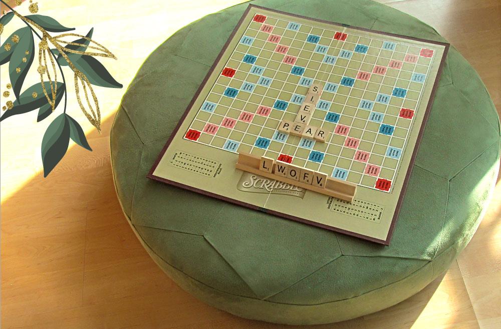 Round floor pouf sewing project, a sage green faux suede star pieced pouf holding a Scrabble board as a low table