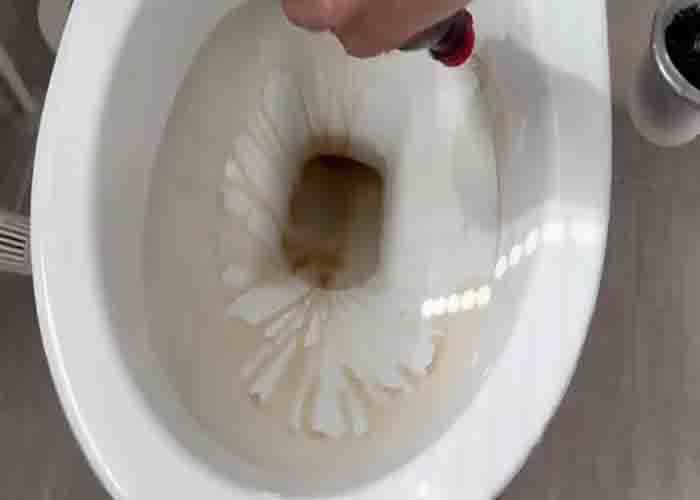 Spreading the coca-cola cleaning solution into the toilet