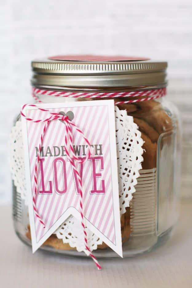 A wide mouth glass jar filled with chocolate chip cookies, tied with twine and a made with love gift tag