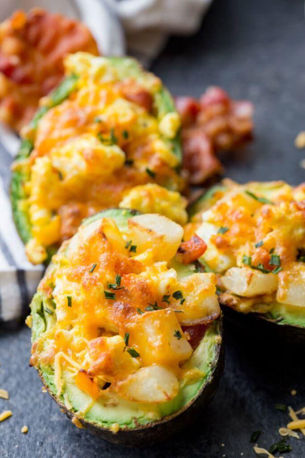 Breakfast stuffed avocado halves filled with scrambled egg, bacon and potato under melted orange cheddar