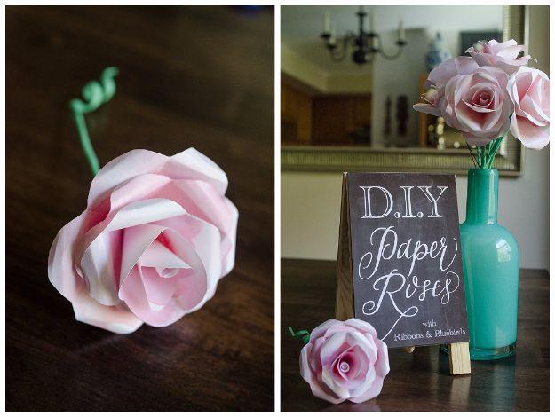 Watercolor paper rose, a pale pink watercolored paper rose beside more roses in a teal vase and a chalkboard sign