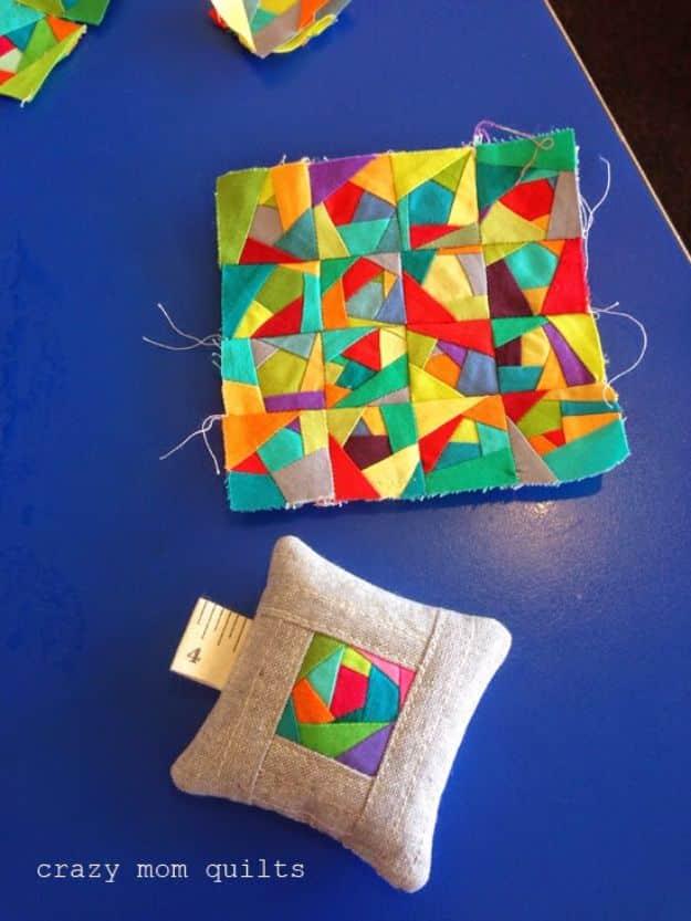 Quilting scraps mini spiderweb quilt in bright solid wedges on white beside a small linen pincushion
