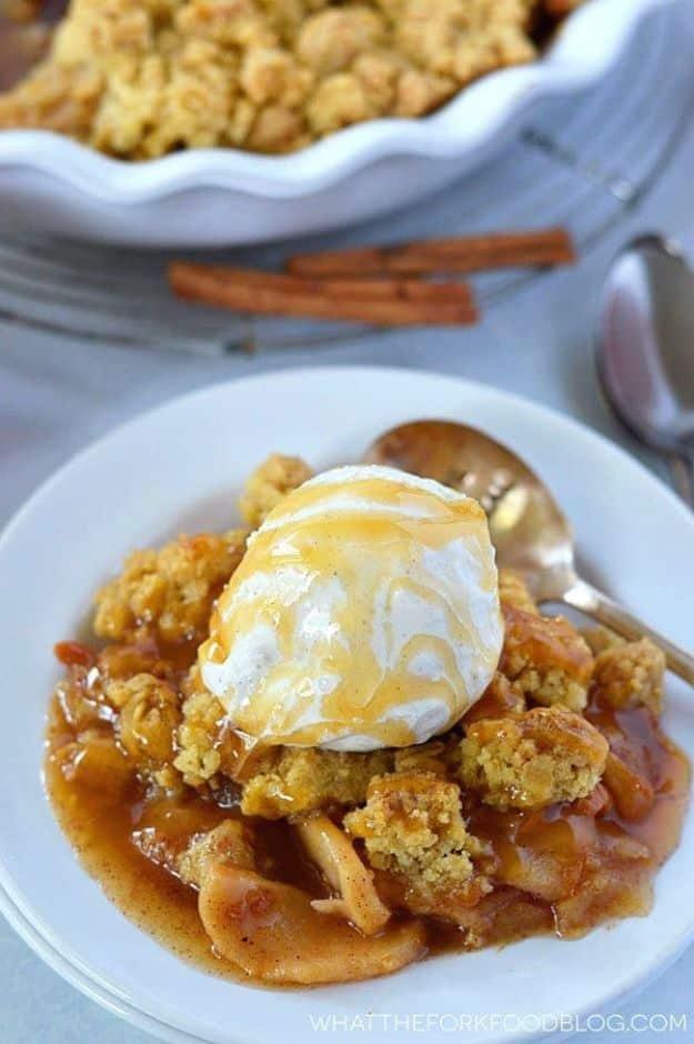 Gluten free caramel apple crisp in a white bowl under a scoop of vanilla ice cream and caramel sauce