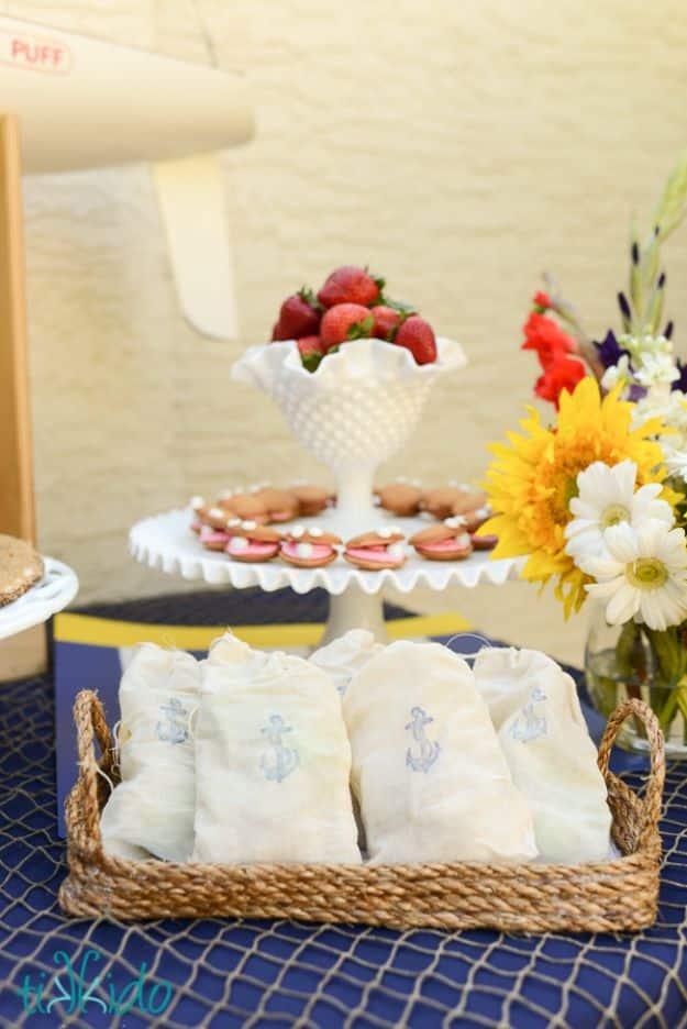 A round serving tray edged in coiled sisal rope rests on a wooden table beside two mugs and a folded linen napkin