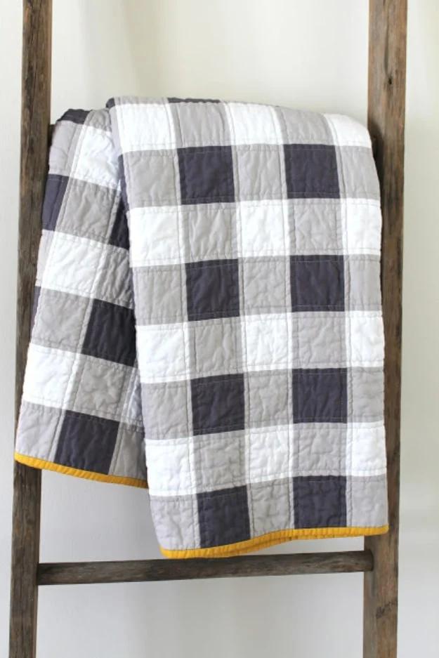 Sewing projects for boys gingham patchwork quilt in white, gray and charcoal squares with yellow binding on a wooden ladder