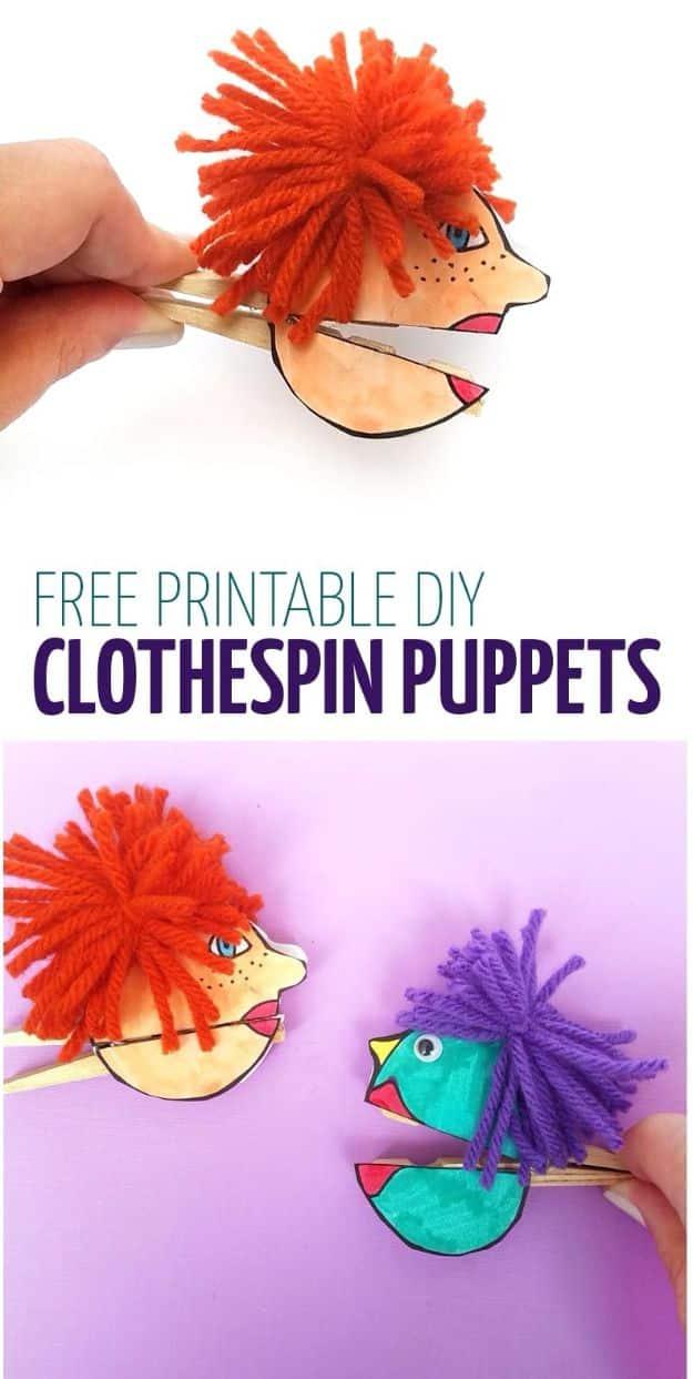 Two clothespin paper puppets shaped like birds with orange and purple yarn hair, one held between fingers