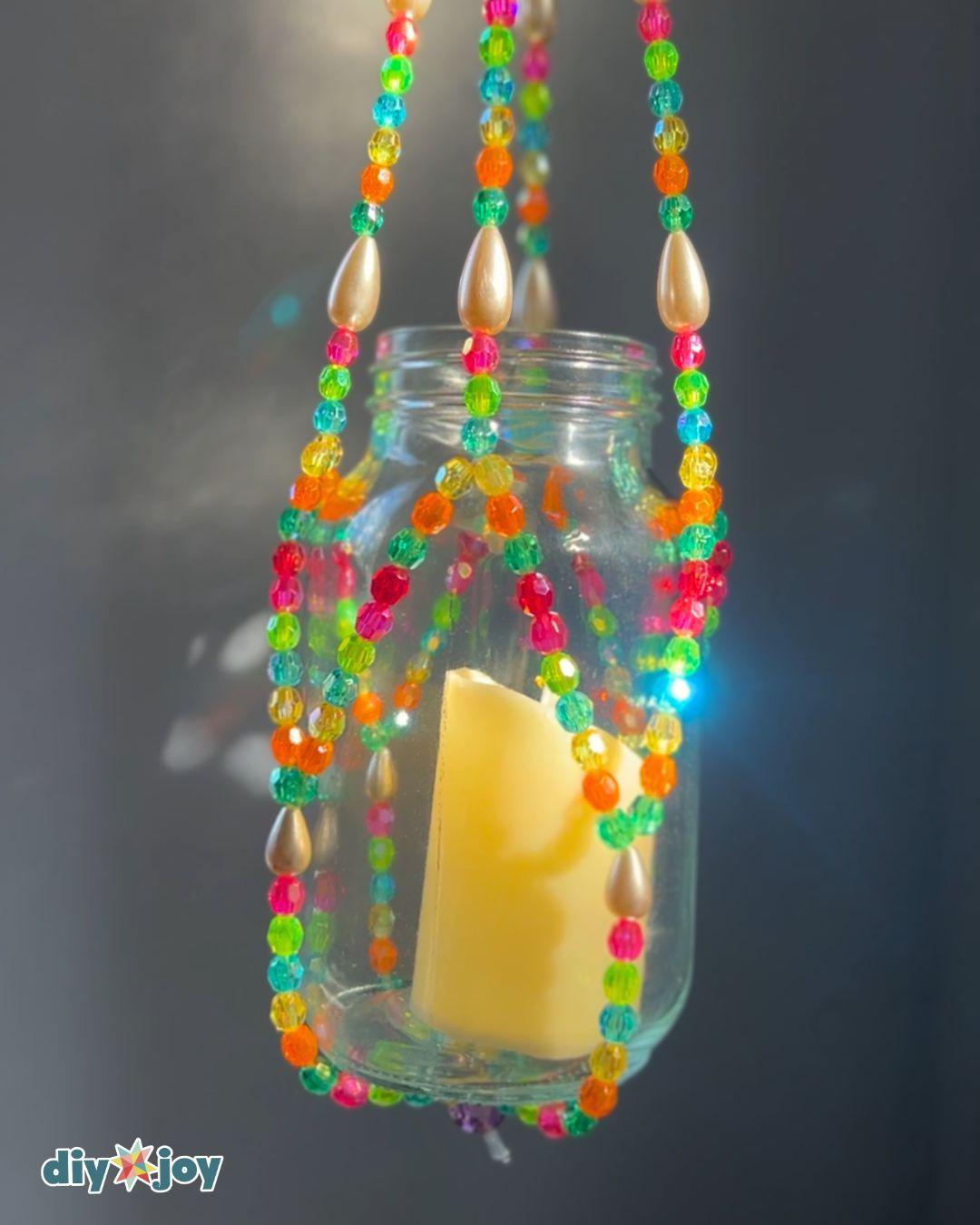 Beaded lantern tutorial step showing all eight strands gathered and tied into one secure knot below the candle jar