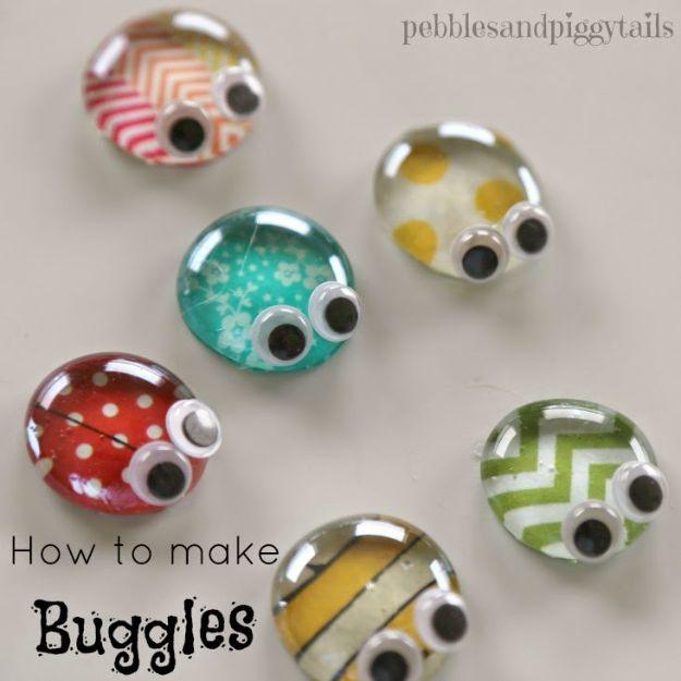 Six clear glass gem bugs with patterned paper backs and large googly eyes, scattered on a white surface, with a typeset title