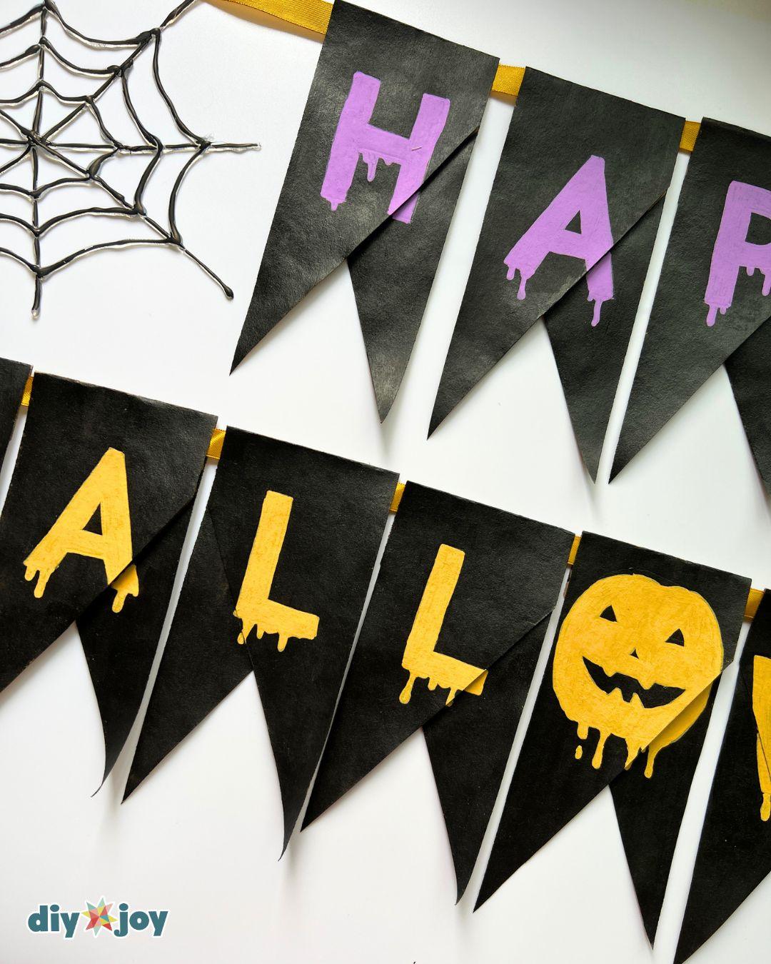 Halloween banner ideas - closeup of the drippy purple lettering on black toilet paper roll bunting, hand painted.