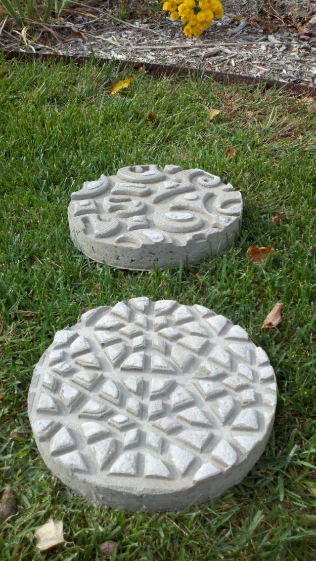 Two round concrete stepping stones with raised geometric patterns pressed into them, set in green grass