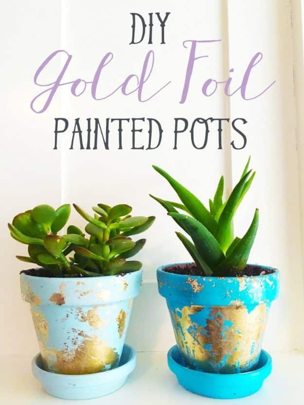 Three terracotta pots painted white with a torn band of real gold leaf around the rim, grouped on a sunlit windowsill.