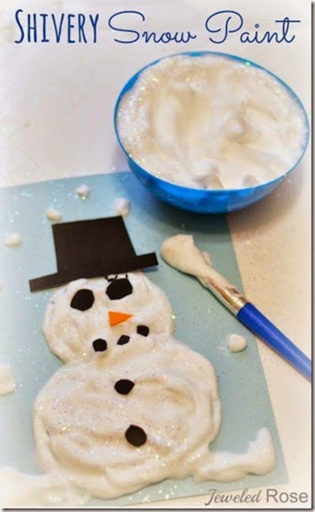 Puffy white snow paint snowman on blue paper with a black paper hat, next to a bowl of paint and a brush