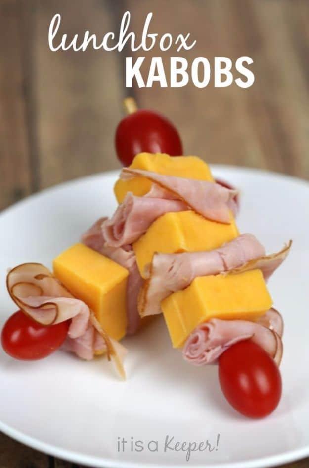 Lunch box kabobs with cheddar cubes, folded ham and cherry tomatoes on short skewers on a white plate