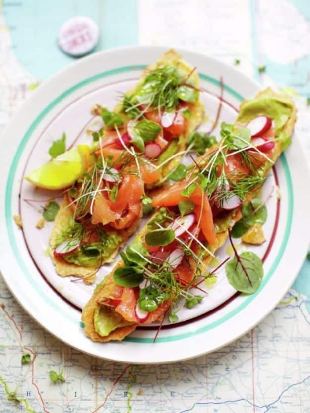 Smoked salmon toasts on crispbread with mashed avocado, sliced radish, fresh dill and micro leaves on top