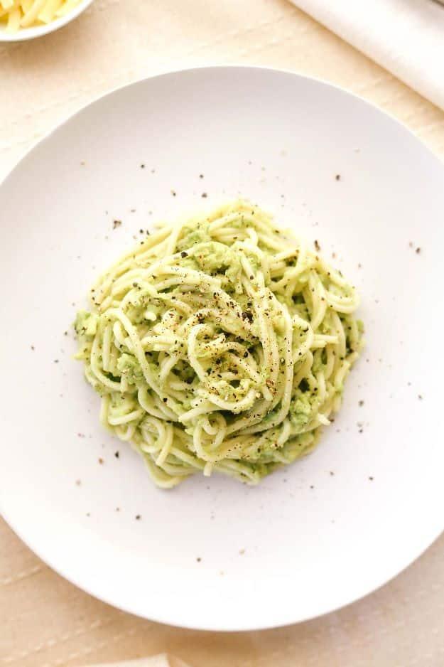 Keto creamy avocado pasta, a white plate of pale green noodles tossed in a smooth avocado and cream sauce