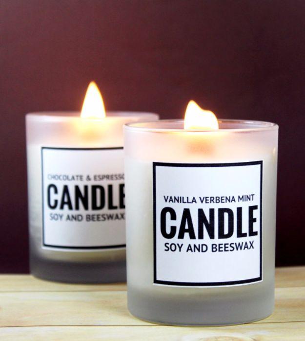 Free printable candle labels on two lit frosted glass soy and beeswax candles on a pale wooden table