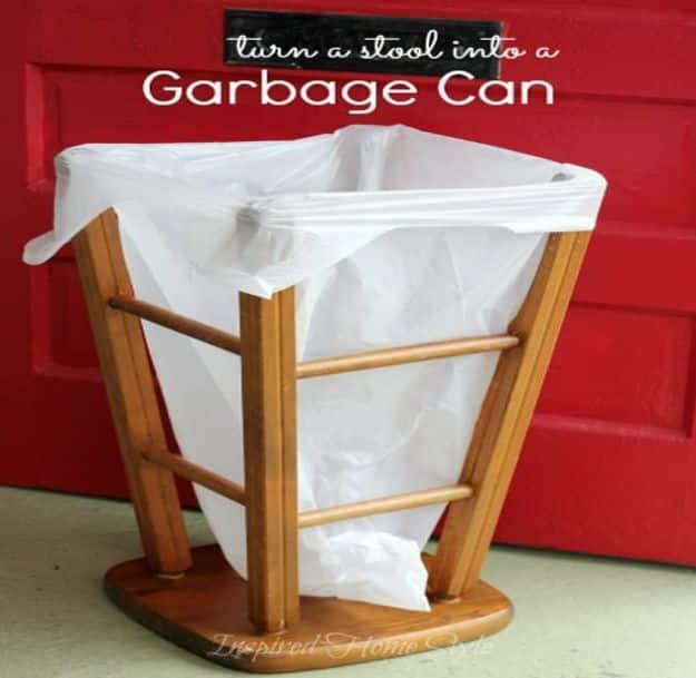Wooden bar stool turned upside down with a white trash bag stretched over its legs, against a red garage door