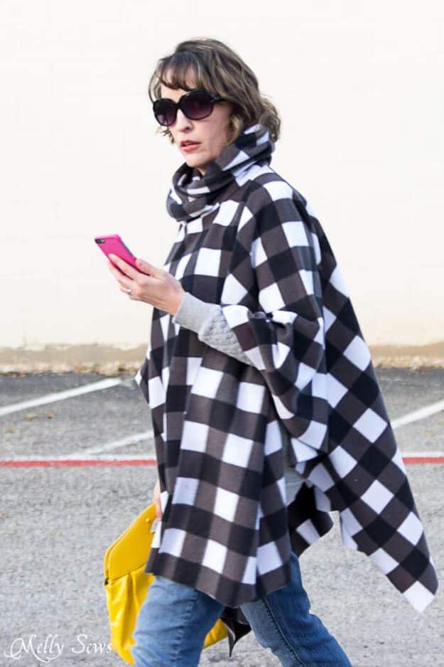 DIY clothes for winter, a woman outdoors in a black and white buffalo check fleece poncho with a cowl neck