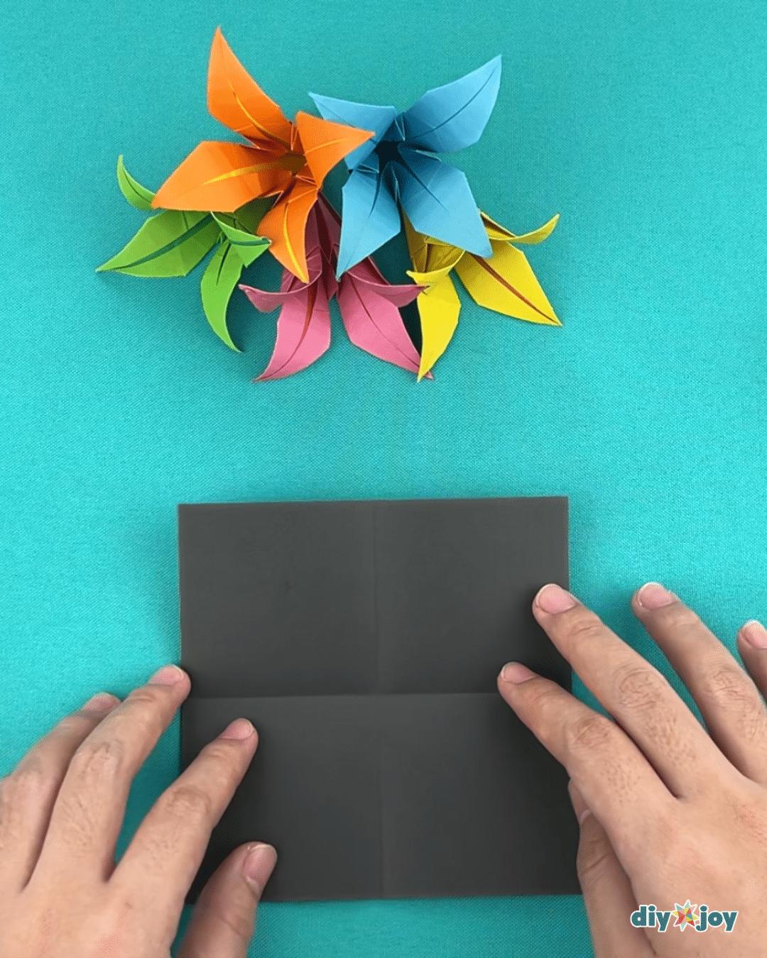 How to make a lily flower from paper, showing the first halving fold in the origami paper flower tutorial
