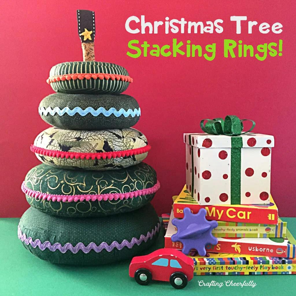 A stacking toy of five stuffed green fabric rings trimmed with pom poms and ric rac and a felt star on top by a gift box